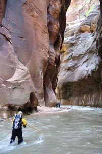 A person in a yellow backpack in a riverDescription automatically generated