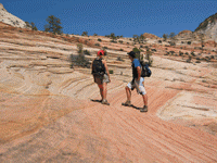 A couple of people hiking on a rocky hillDescription automatically generated
